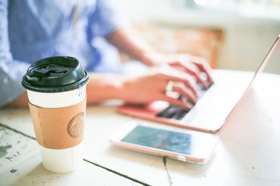Café para llevar junto a un portátil