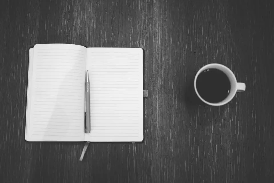 Cuaderno y café sobre una mesa oscura